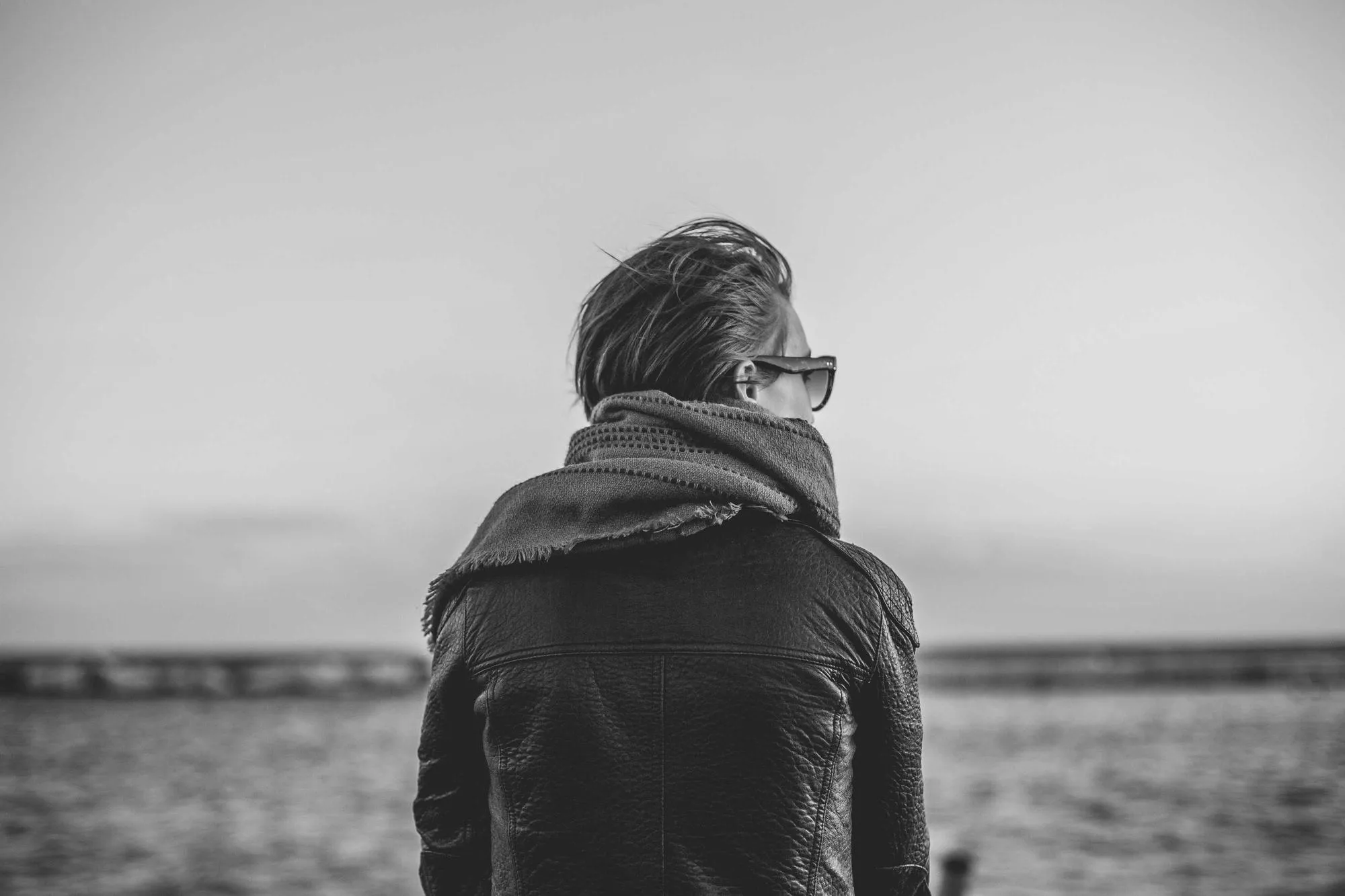 Man in a heavy coat waiting at a crossing, looking away