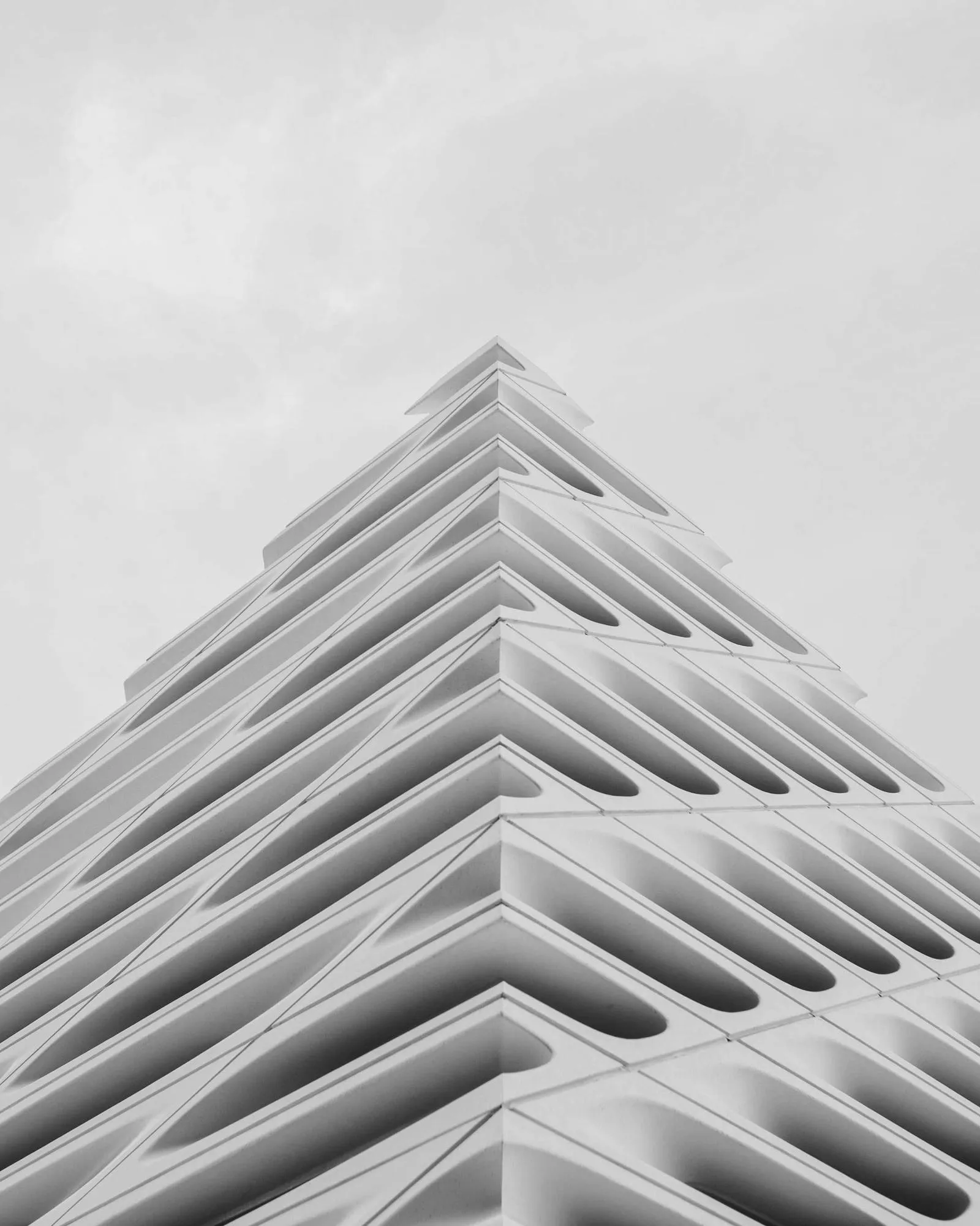 Monolithic concrete facade with repeating window grid in hard light